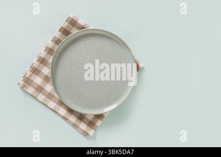 Empty ceramic blue plate and checkered napkin on plain light blue background. Table setting for Father Day. View from above. Copy space Stock Photo