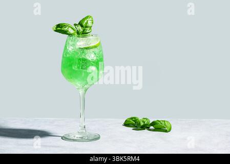 Green Parrot Cocktail on gray background, copy space. Gin Basil Smash drink with ice cubes. Refreshing summer basil cocktail. Stock Photo
