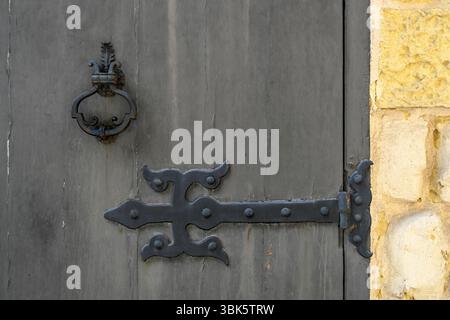 Old ornate cast iron door hinge and knocker on wooden door Stock Photo
