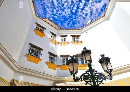 Malaga Benalmadena white walled diagonal faced house and  street lamps against deep blue sky and mackerel cloud Stock Photo