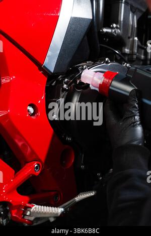 Motorcycle Oil Refill. Replacing engine oil in a sports motorcycle to ensure top performance and engine longevity. Precision oil fill operation on a r Stock Photo