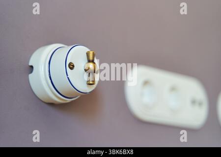Retro style light switch and socket on dark pink wall Stock Photo