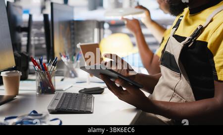 PC based solar technician reviews automation data in production factory, manufacturing industry focused on renewable energy. Worker tracks solar panels and machine performance. Camera A. Stock Photo