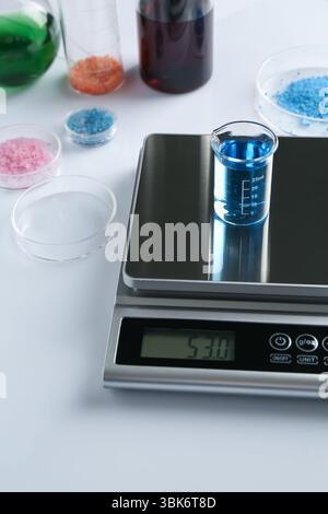 Scale with beaker of sample and other laboratory glassware on black ...