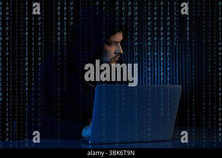 Cyber attack. Hacker working on laptop against dark background. Binary code around him Stock Photo