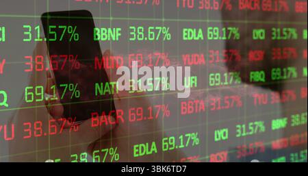 Holding smartphone with left hand in office, displaying stock data on transparent panel, copy space Stock Photo