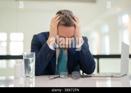 Tired man having a terrible headache. Exhausted man feeling unhealthy, upset about headache illness. Stressed middle-aged man having headache Stock Photo