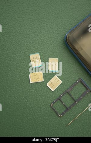 Multiple SIM cards and a smartphone on a green surface Stock Photo