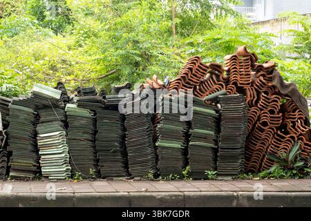 Pile of tiles and bricks are stacked on the sidewalk. The pile is large and he is in disarray Stock Photo