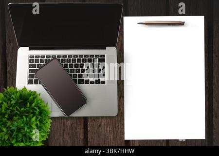 Smartphone on a laptop on side of paper and pen Stock Photo