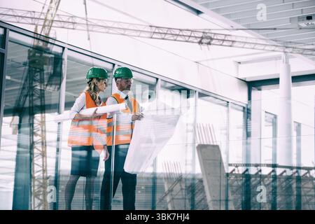 Male and female engineers discussing over blueprint Stock Photo