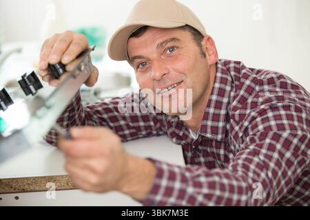 young contractor repairing oven in kitchen Stock Photo
