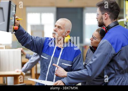 senior engineer and apprentices checking computer in a factory Stock Photo