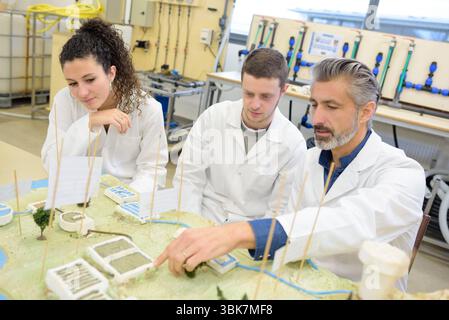 students and teacher in white jackets performing irrigation experiment Stock Photo