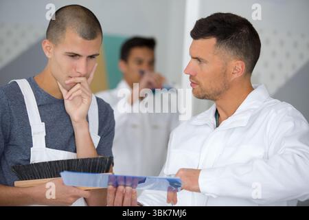 apprentices learning how to paint with a thick brush Stock Photo