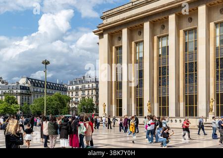 Paris cityscape with Trocadéro architecture, crowds of people, and cloudy sky. Light tan building facade. Stock Photo