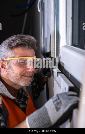 A professional installer checks the horizontal alignment of a newly installed window using a spirit level to ensure proper leveling and fit Stock Photo