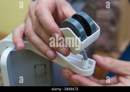 Man mounting a plastic wheel on an electric heater Stock Photo