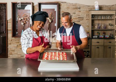 Chefs showing tray of uncooked appetizers making thumbs up sign during cooking course Stock Photo