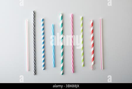 Collection of tubular drinking straws with different patterns and colors isolated on a white table. Top view. Stock Photo