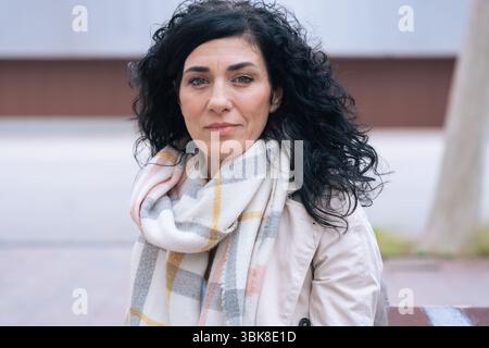 individual portrait Confident woman with curly black hair and scarf smiling  Stock Photo