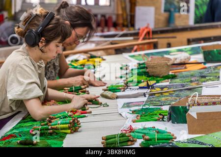Weavers Margot and Aurelie at a flat loom (basselisse), as used in traditional tapestry making. Cité internationale de la tapisserie in Aubusson Rue Williams Dumazet, Aubusson, Nouvelle-Aquitaine, France Stock Photo