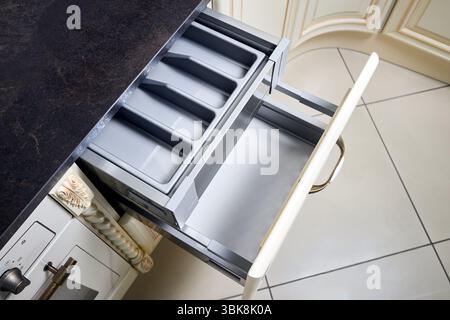 Solutions for placing utensils in classic kitchen - horizontal sliding pull out drawer shelves storage in a cupboard for kitchenware cookware under st Stock Photo