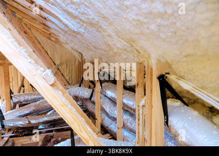 Workers are installing insulation in an attic, wooden beams ductwork for efficient heating cooling. Stock Photo