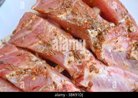 Uncooked seasoned pork ribs on a white cutting board. Isolated on white background Stock Photo