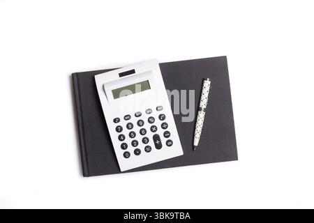 A white solar calculator, a notebook and a pen on a white background with copy space Stock Photo