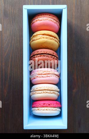 Assortment of beautiful colored Macaron pastries on black wooden table Stock Photo