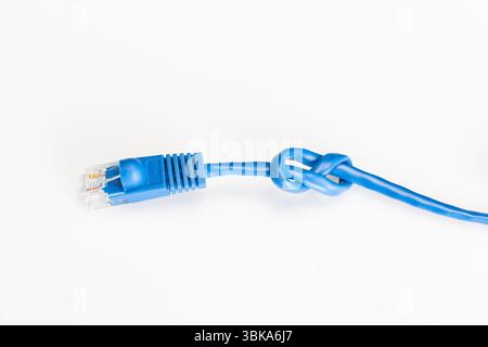 A blue Ethernet cable tied in a knot lies on a white studio background, symbolizing connectivity issues, network problems, or digital frustration in a Stock Photo
