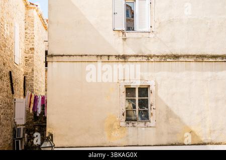 Weathered facade with laundry in the alley. Urban texture, daily life, and Mediterranean authenticity. Stock Photo