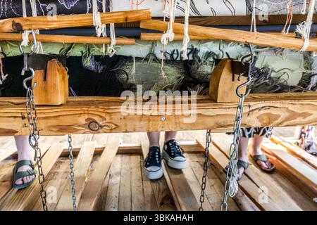 A view beneath the flat loom (basselisse) on which three weavers from the Robert Four workshop in Aubusson are producing Françoise Petrovitch's tapestry 'Hommage à George Sand' to mark the 150th anniversary of George Sand's death. The completed sections of the 23-metre-long tapestry are rolled up again and can only be seen from the back. Even the weavers will not be able to see the complete work until the day it is removed from the loom. Rue Madeleine, Aubusson, Nouvelle-Aquitaine, France Stock Photo