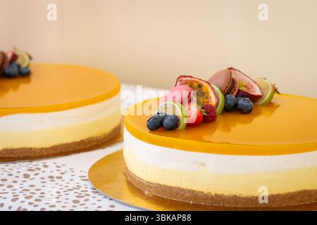 Cheesecake dessert decorated with fresh fruits. A close-up shot of a crafted cheesecake, adorned with vibrant fresh fruits and a delicate macrons. Stock Photo
