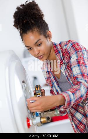 female plumber servicing central heating boiler Stock Photo