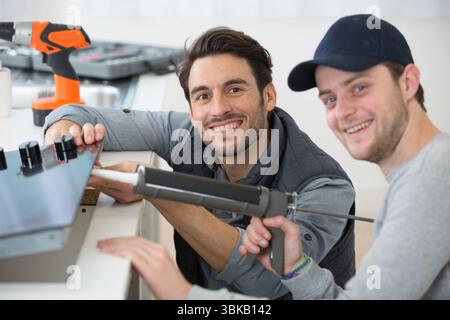 portrait of two men installing kitchen hob Stock Photo