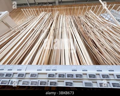 Alicante, Spain - June 18, 2025: Wooden planks neatly arranged on display in a hardware store, showcasing various sizes and textures for construction Stock Photo