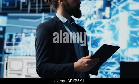 Tech savvy administrator reviewing AI brain programming on a tablet, exploring algorithmic thinking and deep learning through neural networks system. Artificial intelligence coding. Camera A. Stock Photo