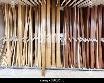 Alicante, Spain - June 18, 2025: Wooden planks of various colors and textures neatly arranged in a hardware store, showcasing different types of wood Stock Photo