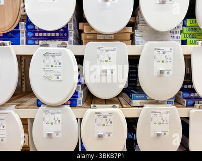 Alicante, Spain - June 18, 2025: Various toilet seats displayed on shelves in a home improvement store, showcasing different styles and designs for Stock Photo
