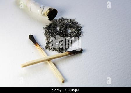 An extinguished cigarette and its ashes form a symbol of death Stock Photo