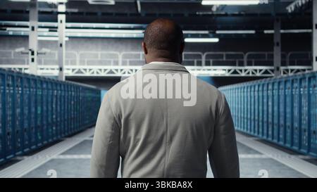 System administrator in data center doing inspection on infrastructure tech handling user requests. African american worker in server farm analyzing traffic patterns of equipment, camera A Stock Photo