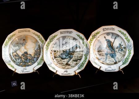 Three patriotic plates - Lanternier Limoges 1917 - JOB - First World War patriotic porcelain plates with motifs from the First World War in the Musée National Adrien Dubouché in Limoges. They served as commemorative and memorial pieces, but also as propaganda tools to strengthen patriotic feelings. These plates were also highly prized by collectors and are now historical documents of the time with artistic and cultural-historical value. There are examples from manufacturers such as Lanternier & Cie, who designed patriotic motifs around 1917. Place Winston Churchill, Limoges, Nouvelle-Aquitaine Stock Photo