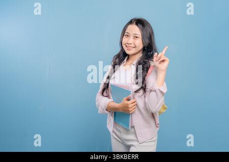 A woman is holding a blue book and pointing to something important. She is smiling and she is happy Stock Photo