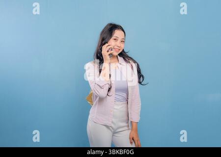A woman is talking on her cell phone. She is smiling and she is in a good mood Stock Photo
