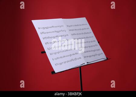 Note stand with music sheets on red background Stock Photo