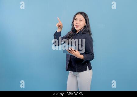 A woman is holding a tablet and pointing to it. She is smiling and she is happy Stock Photo