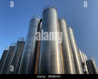 Large stack of metal tanks with a blue sky in the background Stock Photo