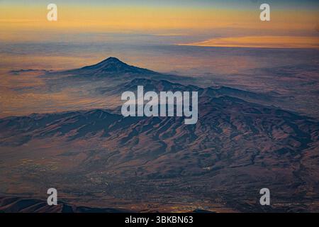 Aerial view of the volcanic mountain range and surrounding plains in central Turkey, photographed from a commercial airplane. The image captures the d Stock Photo